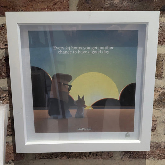 Framed artwork with a sunset scene and motivational quote on a stone wall.